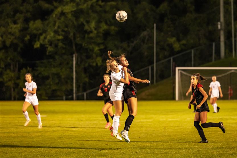 A pair of soccer players prepare to head the ball